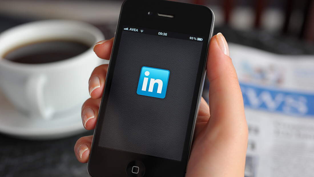 A person holding an iphone with linkedin logo on it.