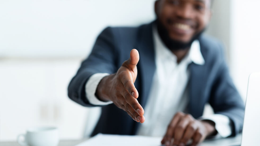 A man in a suit is holding out his hand for someone.