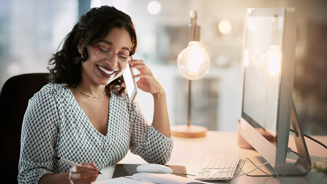 A woman sitting at her desk talking on the phone.