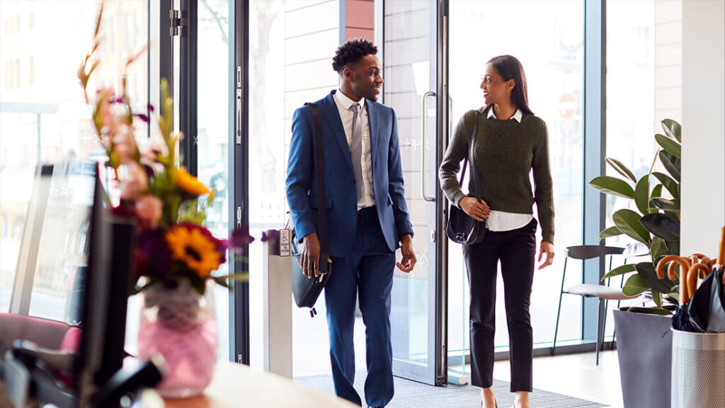 Two people walking in a room with flowers.