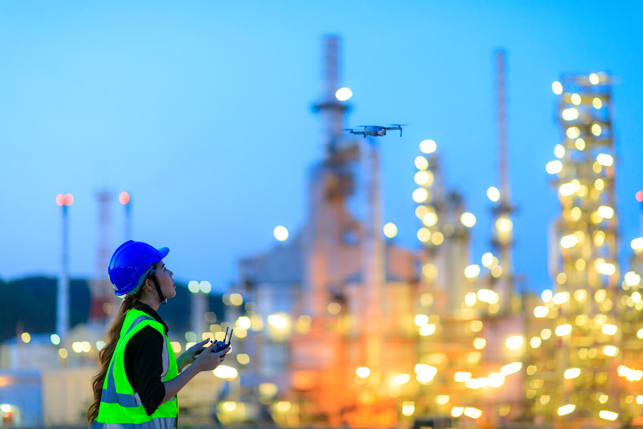 A person in an industrial setting with a plane flying overhead.