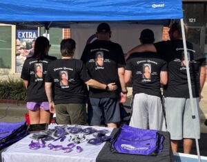 A group of people wearing black shirts and purple bags.