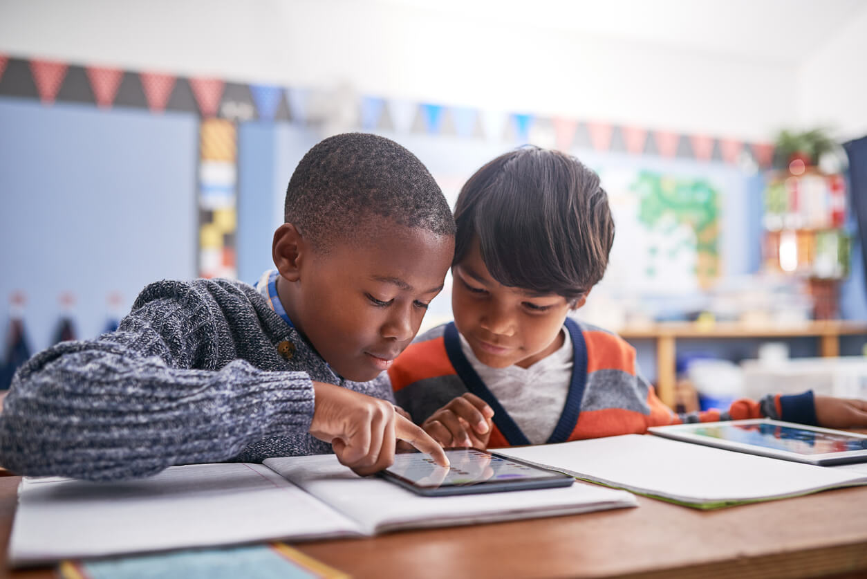 Two boys are playing with a tablet computer.