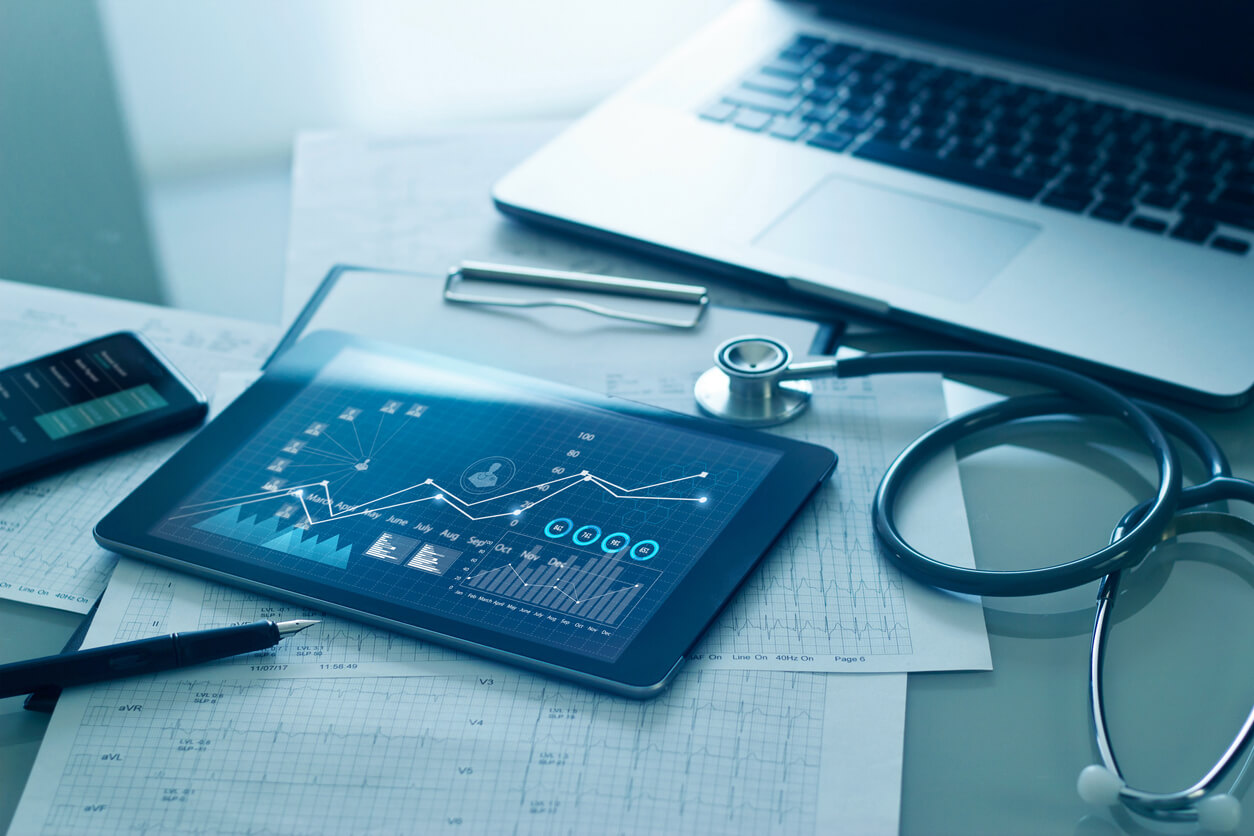 A tablet and laptop on top of papers.