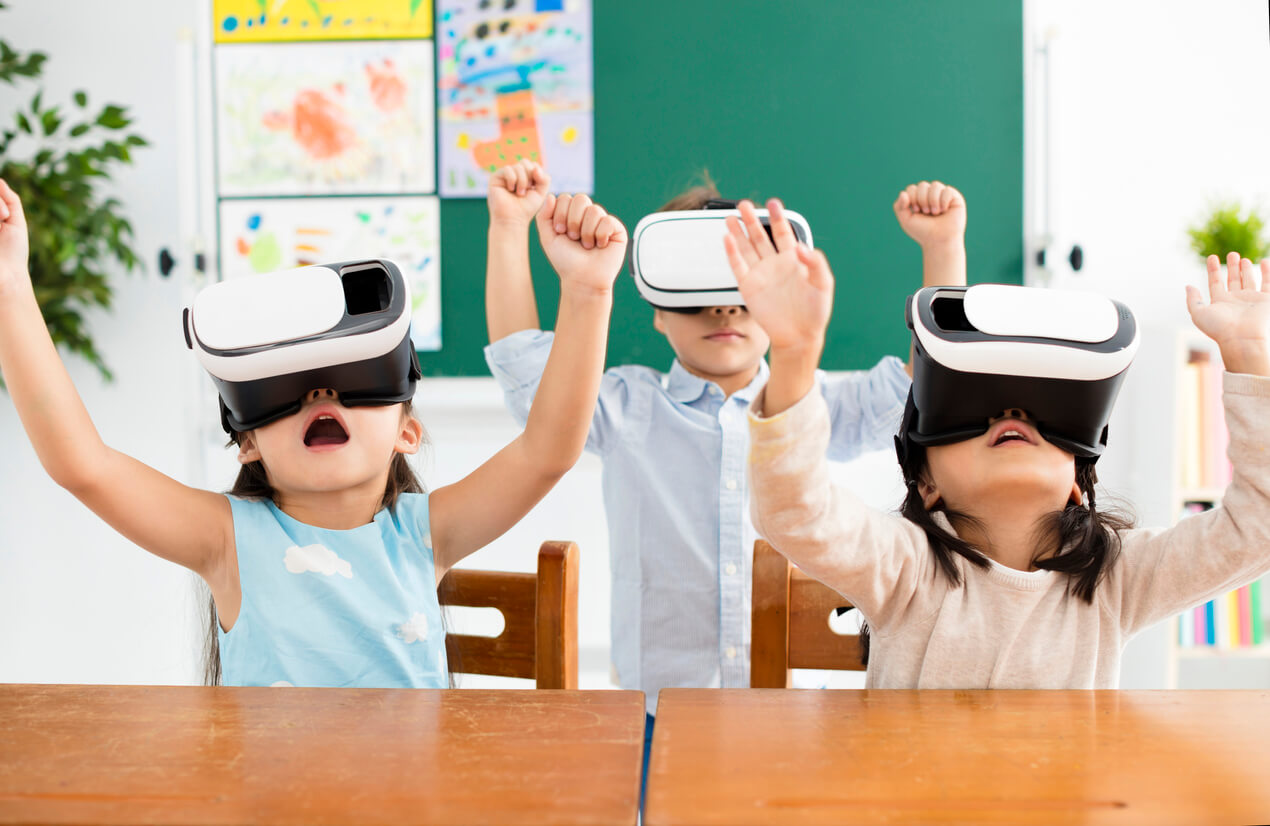 Three children wearing vr goggles in a classroom.