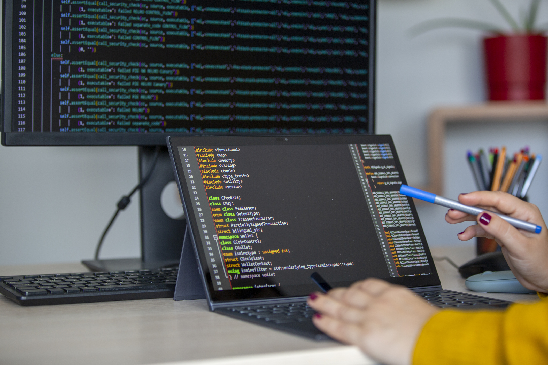 A person using a laptop in front of a computer screen.