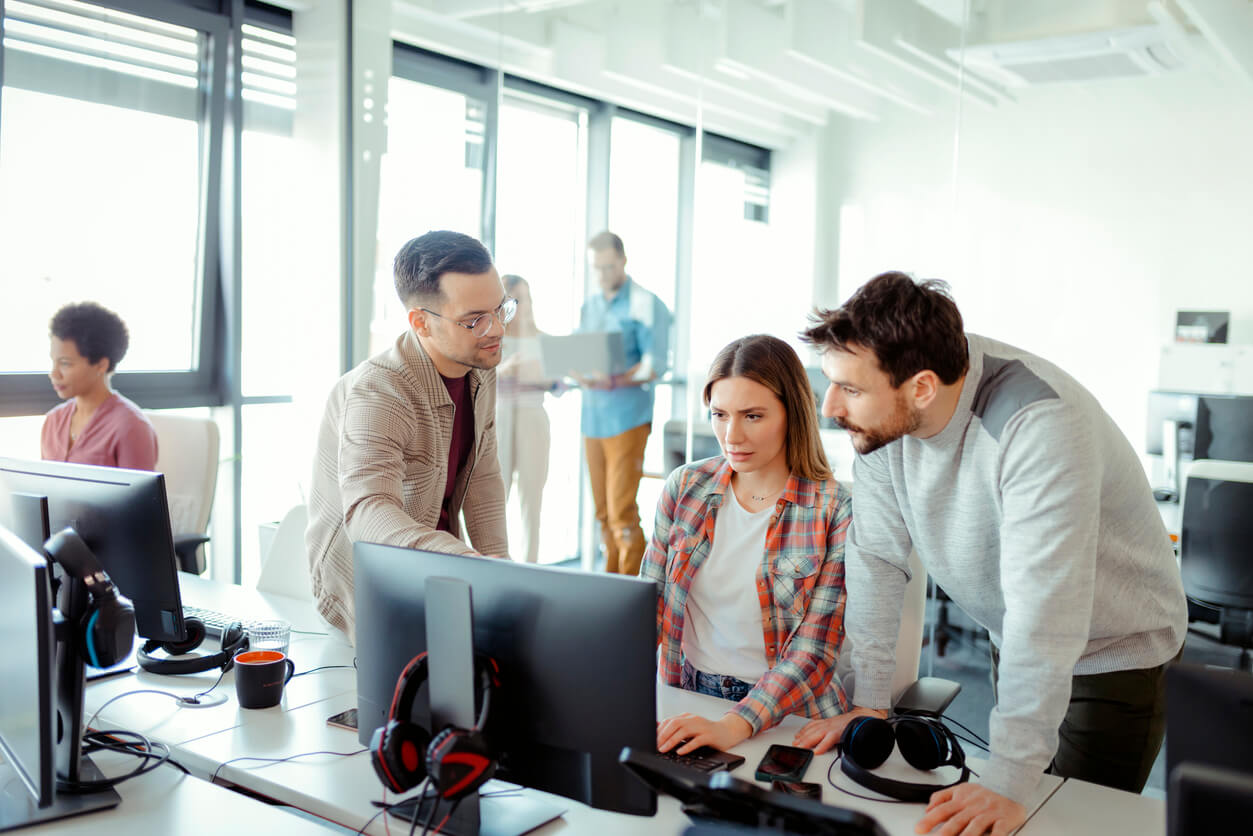 A group of people standing around a computer.